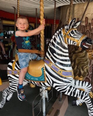 Max is enjoying a ride on a zebra on the carousel